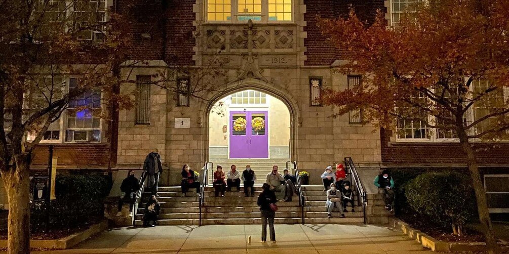 A building entrance with a purple door, steps, and people sitting on the steps. 1