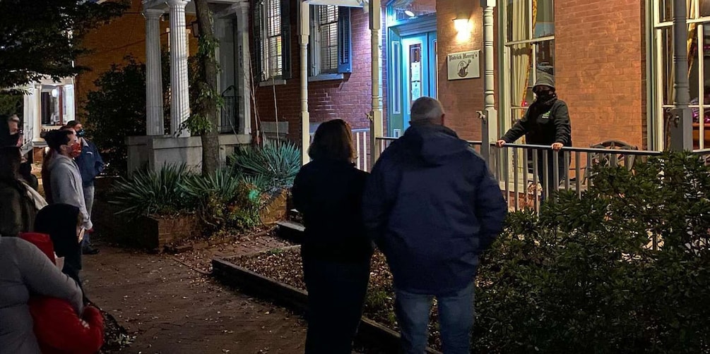 A group of people standing outside a building with a brick facade and a blue door. 5