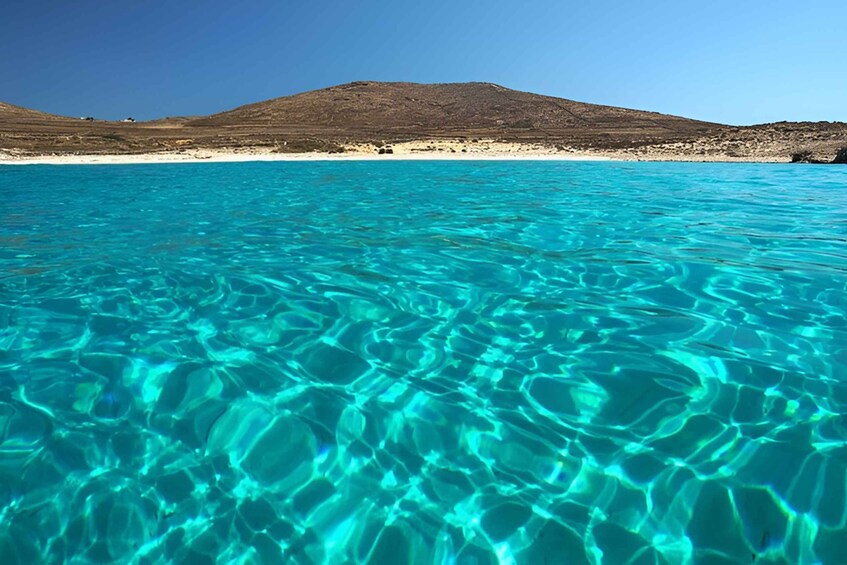Clear turquoise water, a sandy beach, and a hill in the background. 5