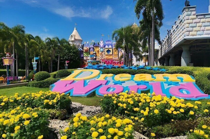A theme park entrance with colorful signage and tropical landscaping. 1