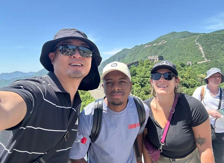 A group of people taking a selfie with a mountainous landscape and a historical wall in the background. 5