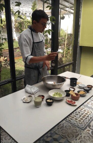 A person in an apron preparing food at a table with various dishes and ingredients. 3
