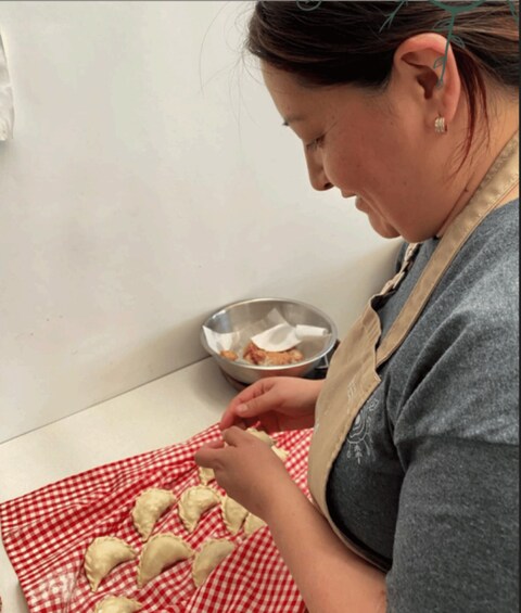A person preparing food, specifically dough on a checkered cloth, with a bowl in the background. 1