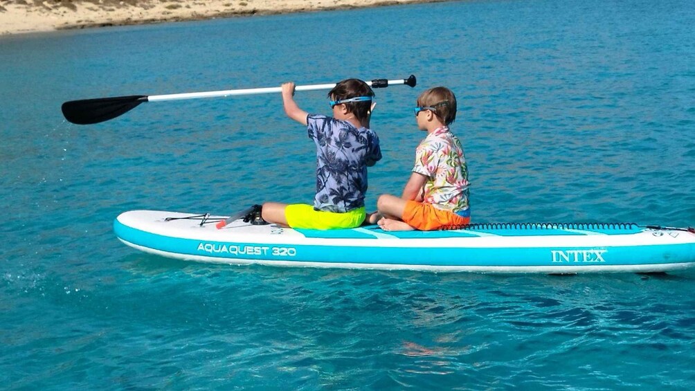 Two people on a blue and white paddleboard in a body of water. 2