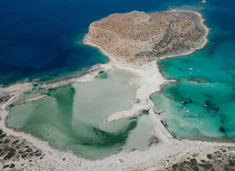 An aerial view of a coastal area with clear blue waters, a sandy beach, and a rocky island. 5