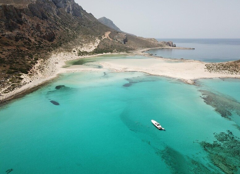 A coastal landscape with clear turquoise waters, a sandy beach, and a boat anchored near the shore. 4