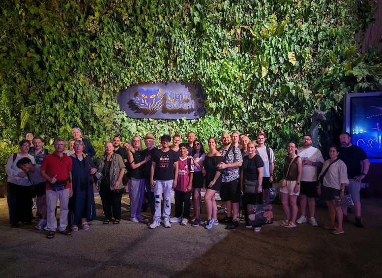 A group of people posing in front of a sign with a leafy background. 3