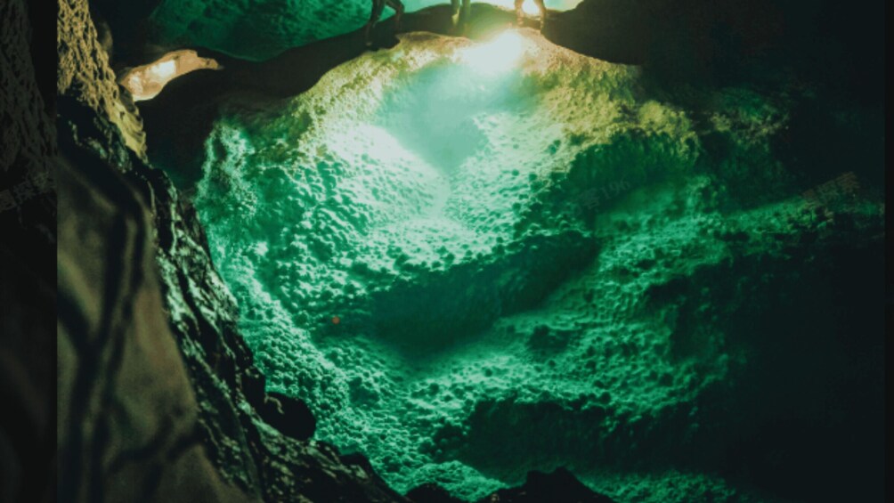 A cave interior with greenish lighting and rough rock surfaces. 1