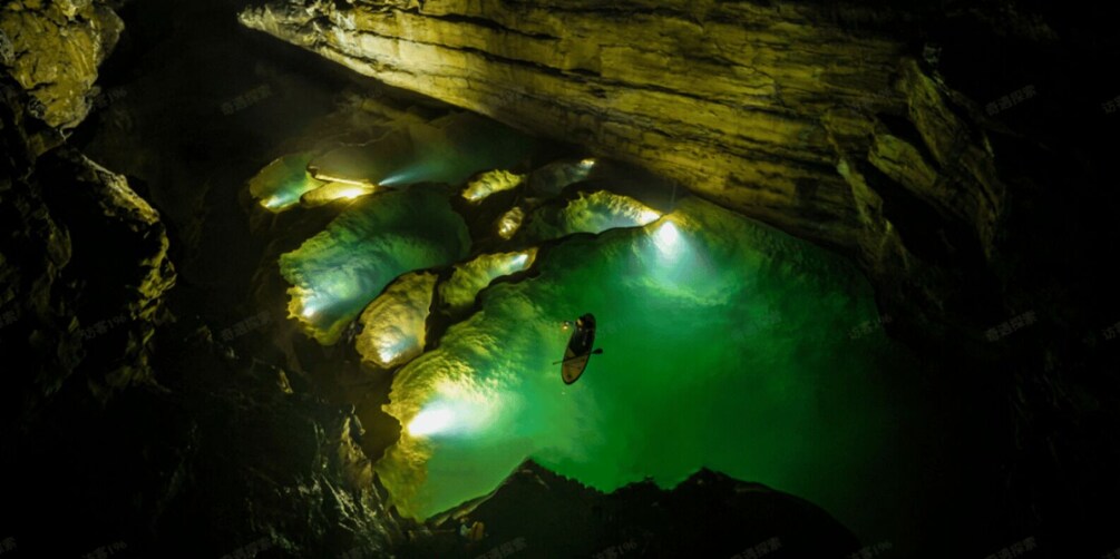 A diver in a cave with greenish water and illuminated rock formations. 3