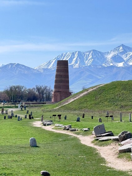 A monument, a cemetery with headstones, and snow-capped mountains in the background. 3