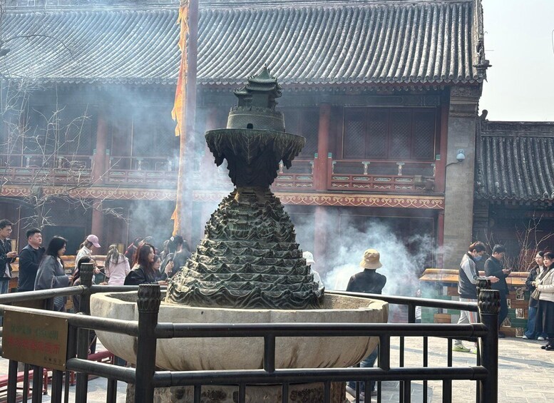 A traditional Chinese building with a stone fountain in the foreground, surrounded by visitors. 5