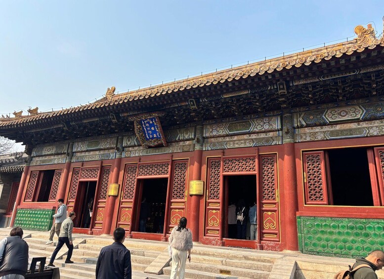 A traditional building with ornate red and green doors, a blue plaque, and a tiled roof. 3
