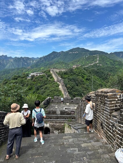 A group of people standing on the Great Wall of China, overlooking the mountainous landscape. 4