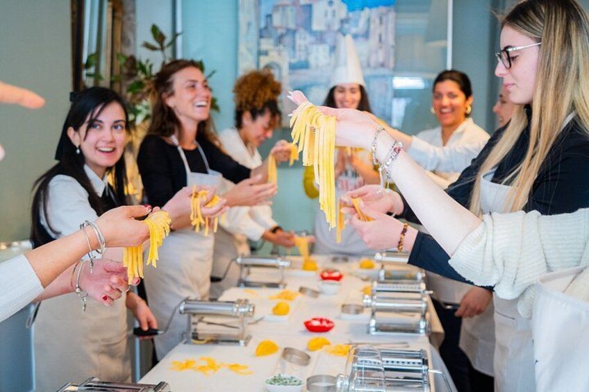 A group of people making pasta in a kitchen. 2
