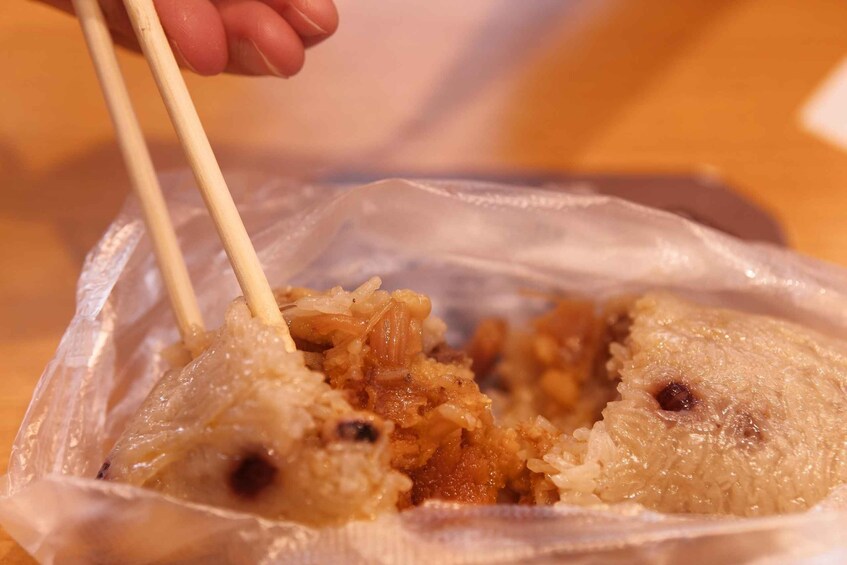 A person using chopsticks to pick up food from a plastic container. 1