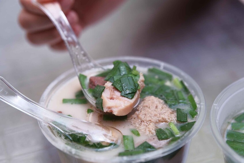 A spoonful of a creamy soup with green vegetables and shredded meat. 2