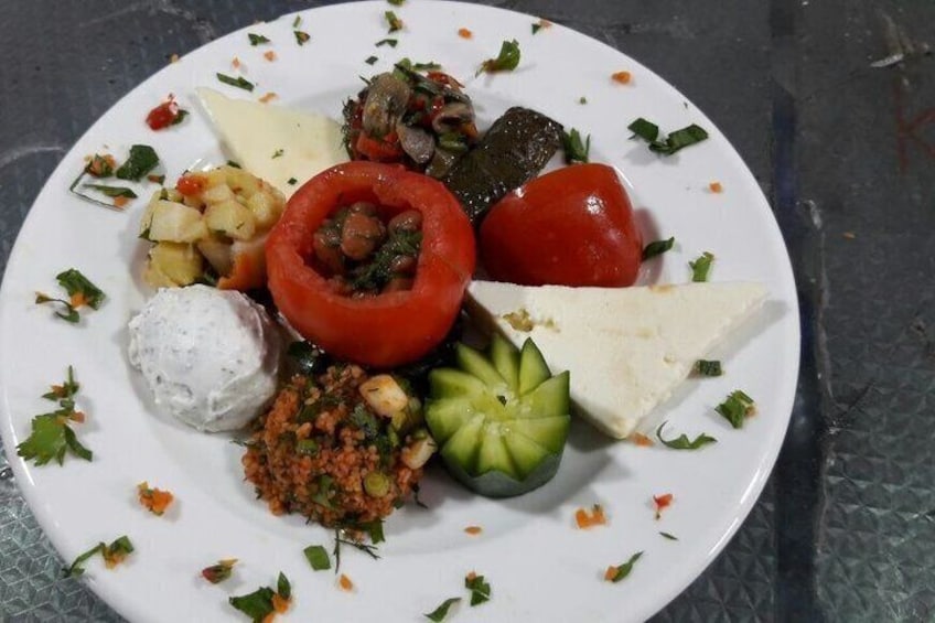 A plate with various foods including a stuffed tomato, cheese, and a small salad. 3
