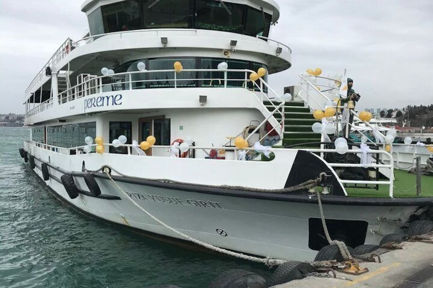 A white ferry named 'perreme' docked at a pier with a green railing and yellow balloons. 1