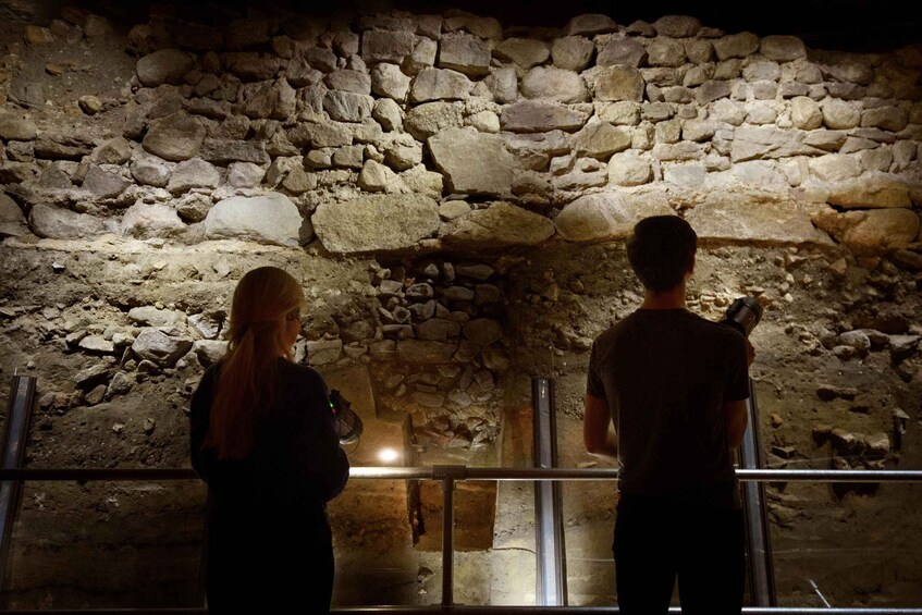 Two people observing a stone wall structure. 4