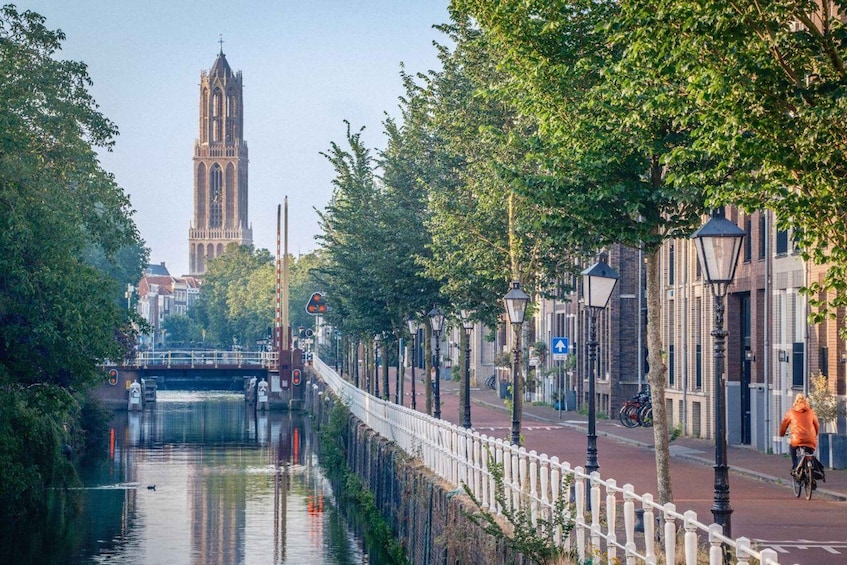 A canal with a bridge, a tower, and a cyclist. 1