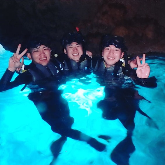 Three people in a swimming pool making peace signs. 2