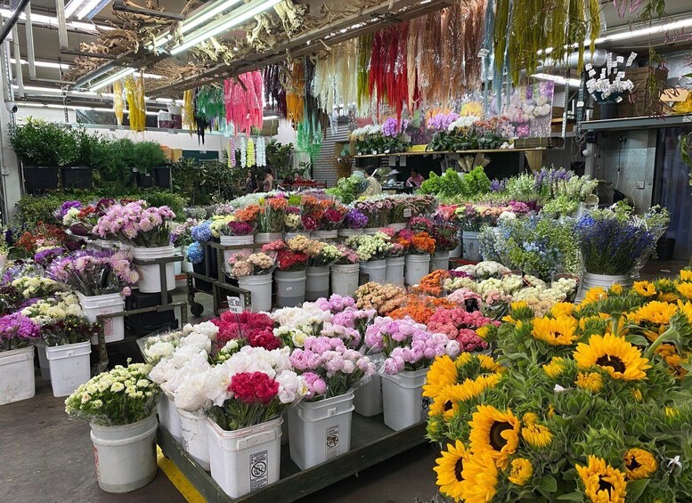 A flower market with various colorful flowers in buckets. 1
