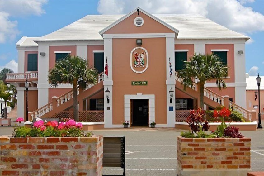 A building with a pink facade, a central entrance, and a coat of arms above the door. 4