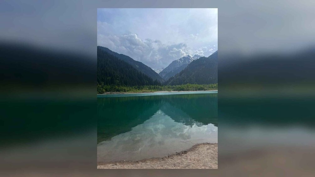 A calm lake surrounded by mountains and dense forests. 3