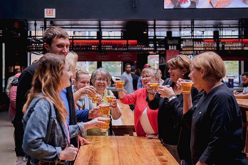 A group of people toasting with beer glasses at a bar. 5