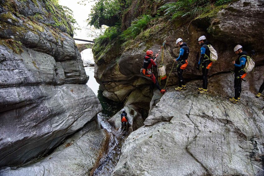 A group of climbers on a rocky cliff with a river below. 2