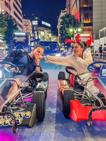 Kaksi go-kartia, joiden kyljessä on merkintä ”SHIBUYA KART”, on pysäköity kadulle, ja taustalla näkyy rakennuksia. 1
