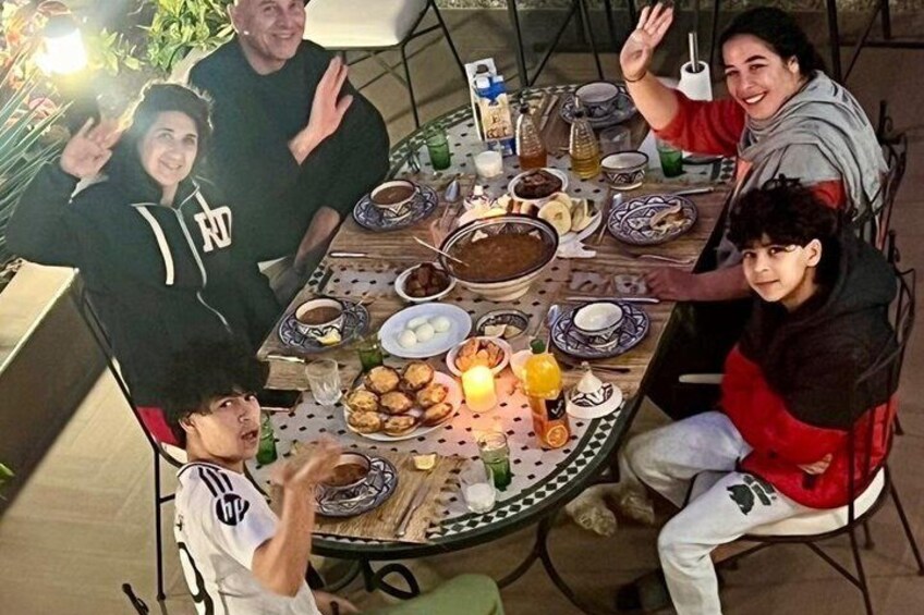 A group of people sitting around a table with food and drinks. 1