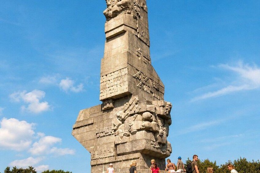 A large stone monument with intricate carvings and a group of people standing in front of it. 5