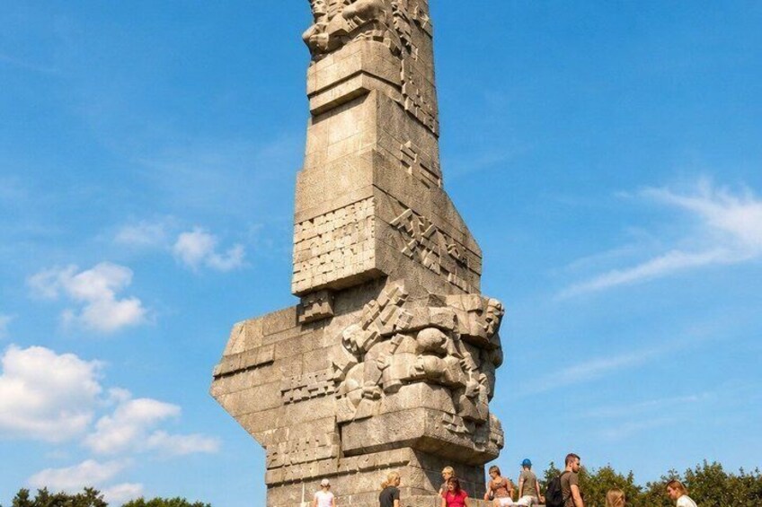 A large stone monument with intricate carvings and a group of people standing in front of it. 5