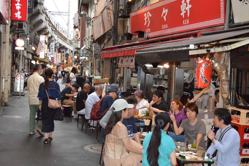 A busy street with people dining at outdoor tables, a red sign with Chinese characters, and a traditional Chinese lantern. 3