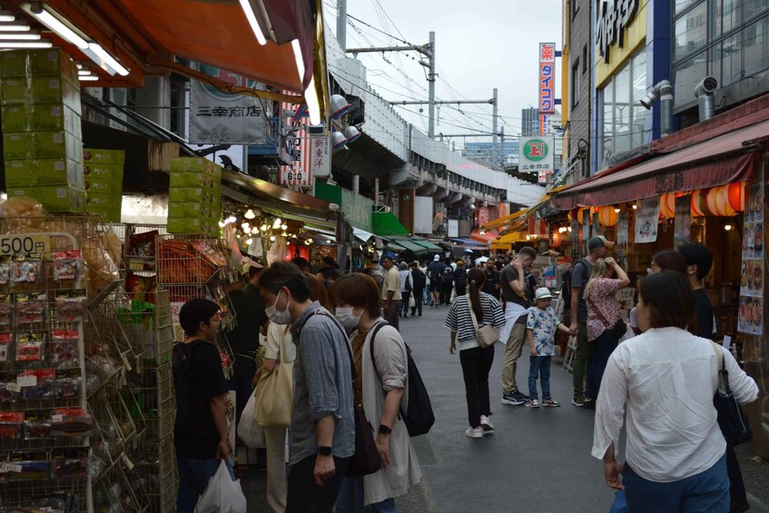 A crowded market street with people shopping and vendors selling goods. 5