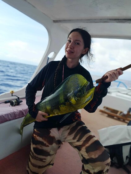 A person holding a large fish on a boat with the ocean in the background. 2