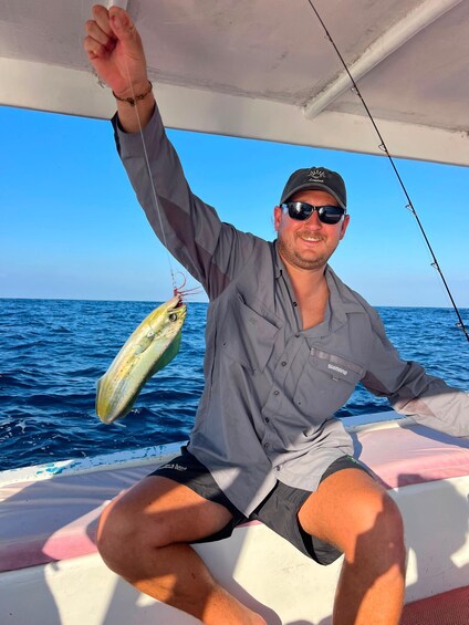 A person on a boat holding a fish. 4