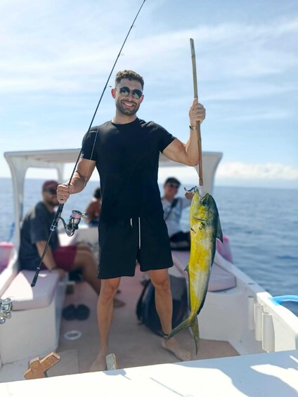 A person holding a fishing rod and a large fish on a boat. 3
