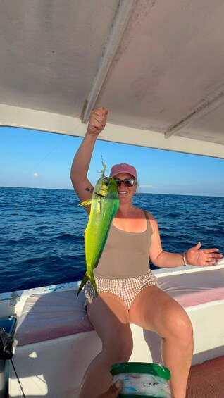 A person holding a fish on a boat with the ocean in the background. 5
