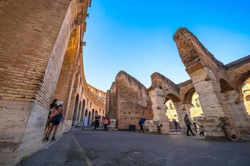 Ancient ruins with arches and brick walls, a paved pathway, and people walking. 2