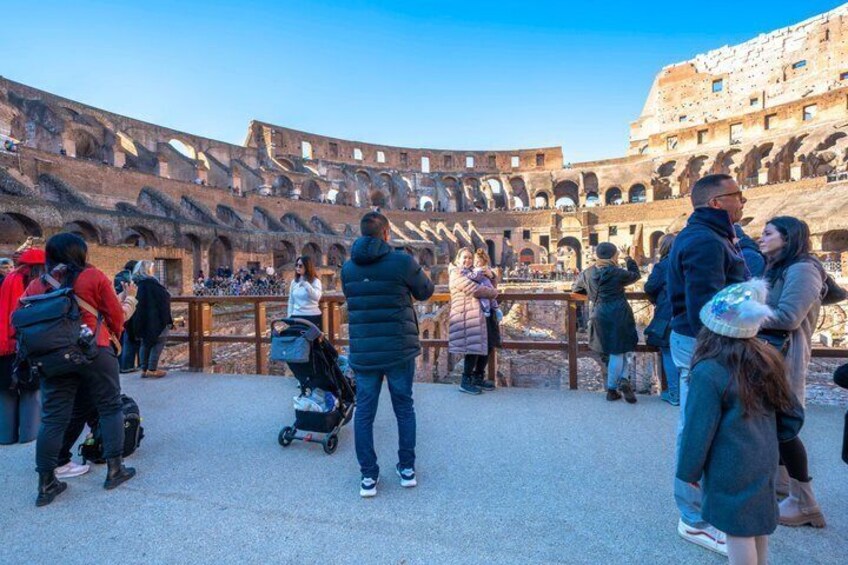 An ancient amphitheater with visitors standing and observing the structure. 1