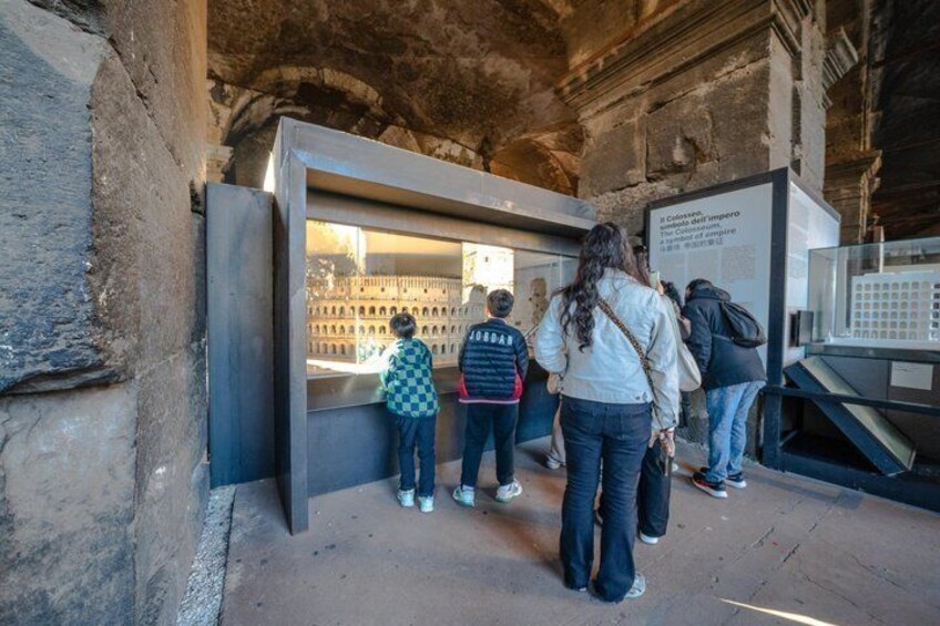 A group of people observing an exhibit in a historical building with stone walls. 5