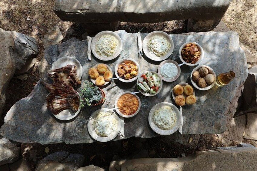 A stone table with various dishes of food, including meat, salads, and bread. 1