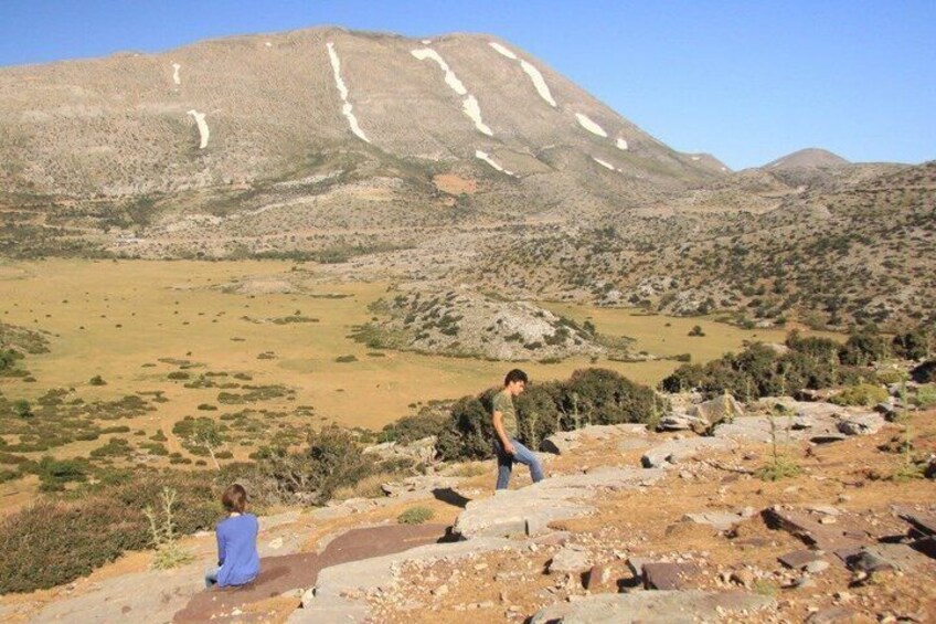 A mountainous landscape with a person sitting and another walking. 5