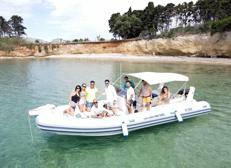 A group of people on a small motorboat in clear waters with a sandy beach and trees in the background. 5