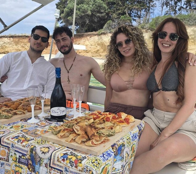 A group of people at a table with food and drinks, outdoors with trees in the background. 3