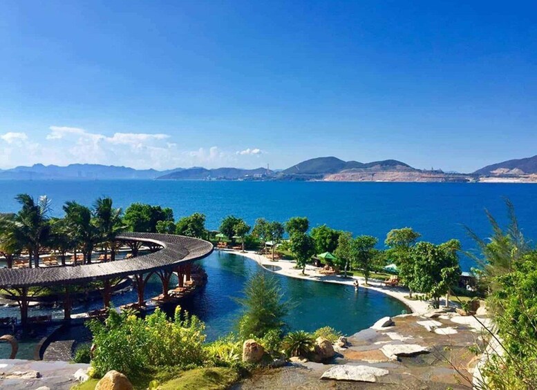 A resort with a circular pool, palm trees, and a view of the sea and mountains. 4