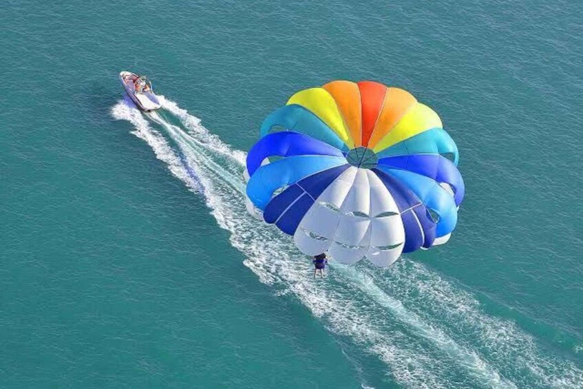 A person parasailing with a colorful parachute over the ocean. 3