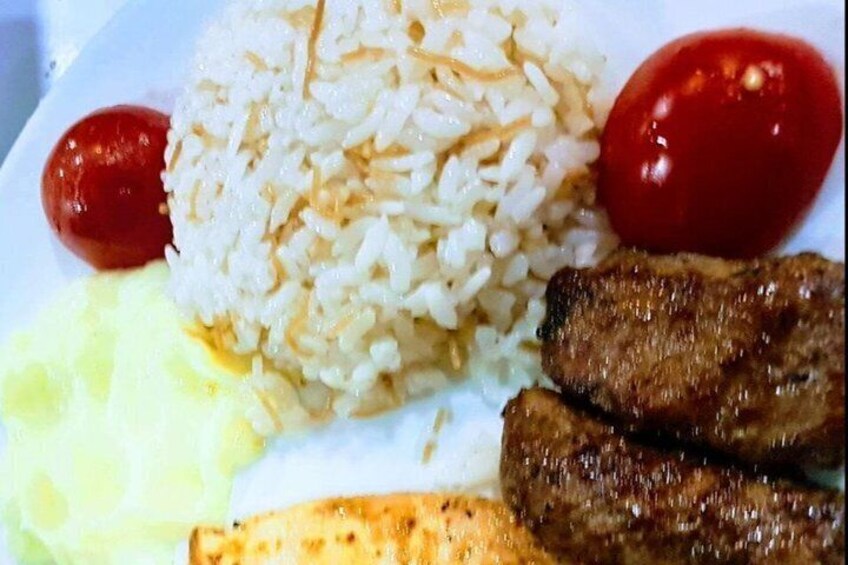 A plate with white rice, two grilled sausages, a slice of yellow cheese, and two cherry tomatoes. 3